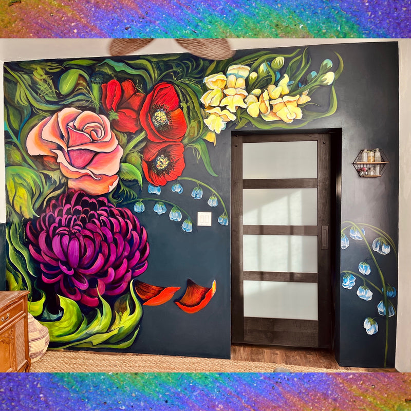 A floral mural on a navy blue wall. There is a dark wood panel door set in the wall, and the mural is comprised of a purple mum, green leaves, white snow bells, a pink rose, crimson poppies, and yellow snap dragons.
